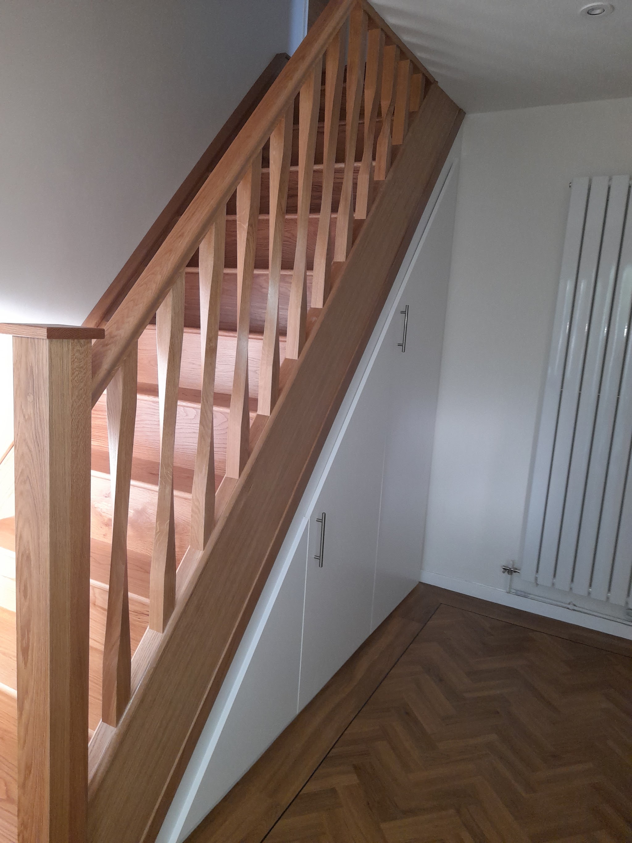 After: new oak handrail and spindles with white cupboards built under the stairs