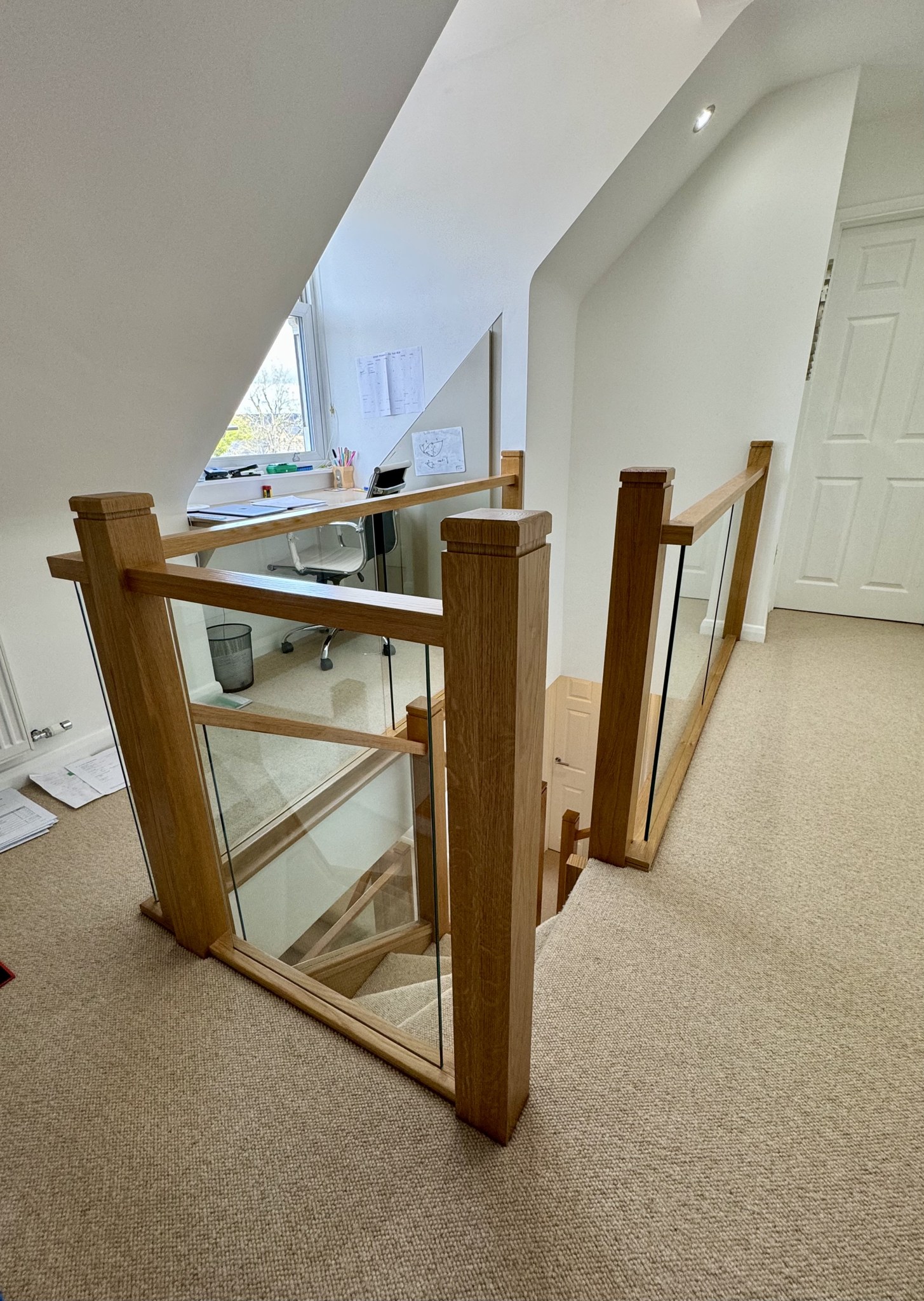 An oak and glass gallery balustrade around a landing
